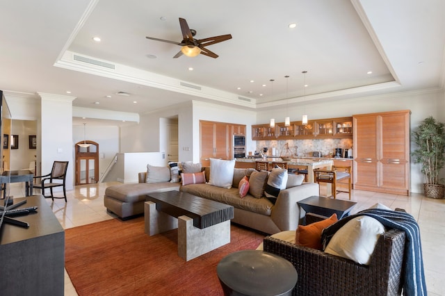 tiled living room with a raised ceiling, crown molding, and ceiling fan