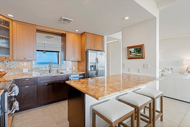 kitchen with a kitchen bar, appliances with stainless steel finishes, light stone countertops, and sink