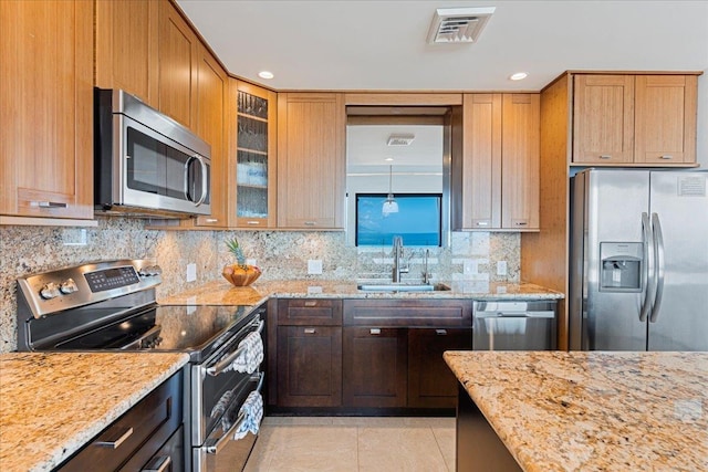 kitchen featuring sink, light stone counters, light tile patterned floors, decorative backsplash, and appliances with stainless steel finishes