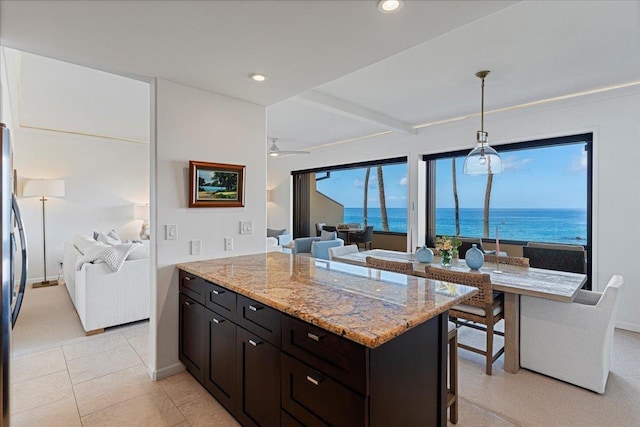 kitchen featuring light stone countertops, ceiling fan, hanging light fixtures, and a water view