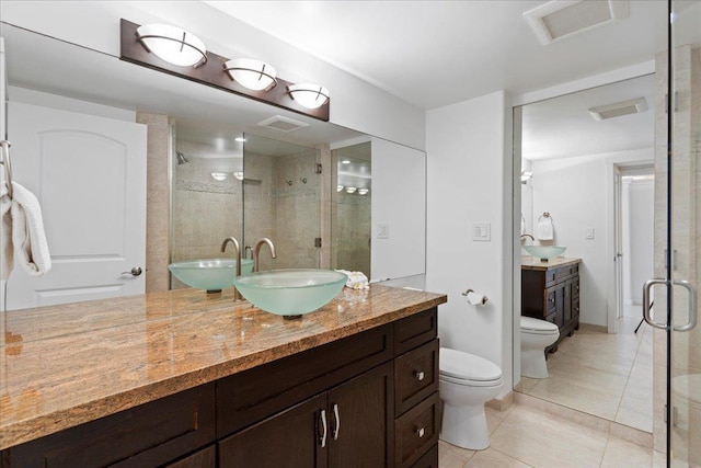 bathroom with a shower with door, tile patterned floors, vanity, and toilet