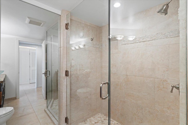 bathroom with toilet, vanity, tile patterned floors, and a shower with shower door