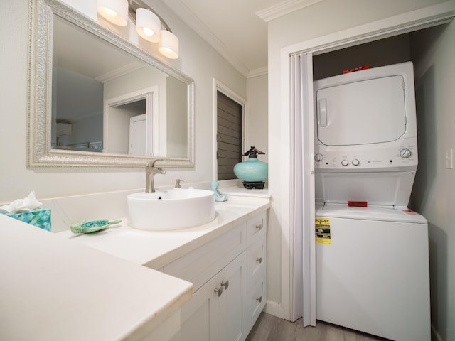 bathroom featuring vanity, hardwood / wood-style flooring, stacked washer / dryer, and crown molding