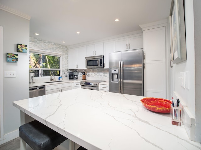 kitchen with a kitchen breakfast bar, sink, light stone counters, and stainless steel appliances