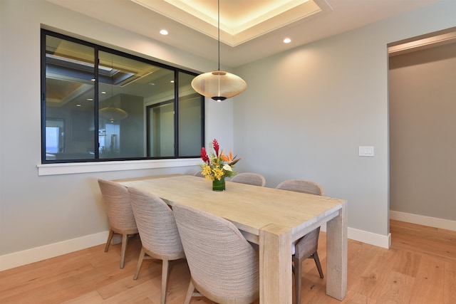 dining space with a tray ceiling and light hardwood / wood-style floors