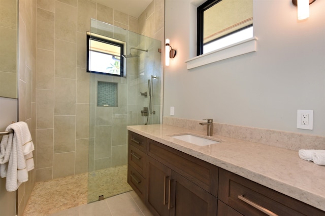 bathroom featuring vanity, tiled shower, and tile patterned flooring