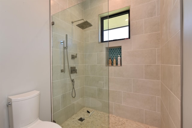 bathroom with a tile shower and toilet