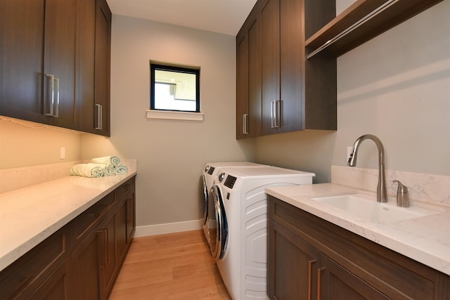 washroom featuring sink, independent washer and dryer, cabinets, and light hardwood / wood-style flooring