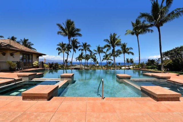 view of pool featuring an in ground hot tub and a water view