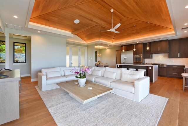 living room with light hardwood / wood-style flooring, wooden ceiling, and a tray ceiling