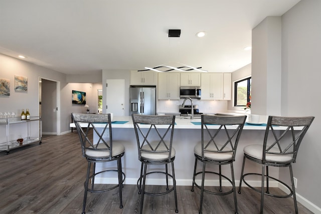 kitchen featuring pendant lighting, a breakfast bar, white cabinetry, dark hardwood / wood-style floors, and stainless steel appliances