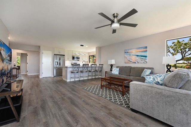 living room with ceiling fan, sink, and dark wood-type flooring