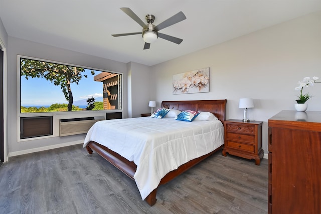 bedroom with a wall unit AC, dark wood-type flooring, and ceiling fan