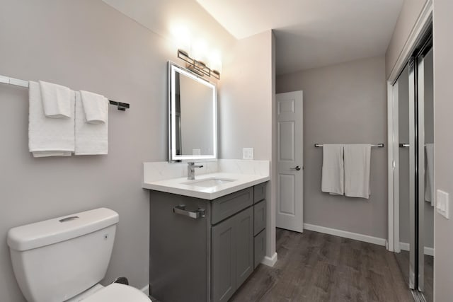 bathroom with toilet, vanity, and hardwood / wood-style floors