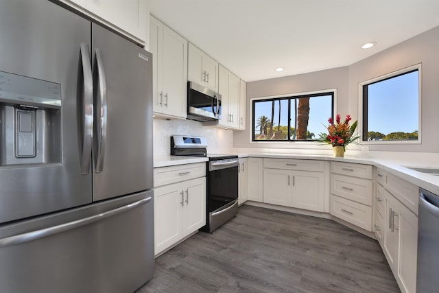 kitchen featuring appliances with stainless steel finishes, dark wood-type flooring, backsplash, and white cabinets