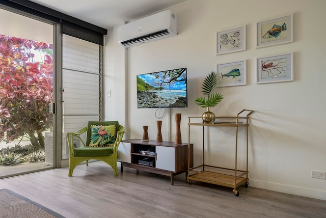 living area with a wall mounted air conditioner and hardwood / wood-style flooring