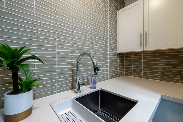 room details featuring white cabinets, backsplash, and sink