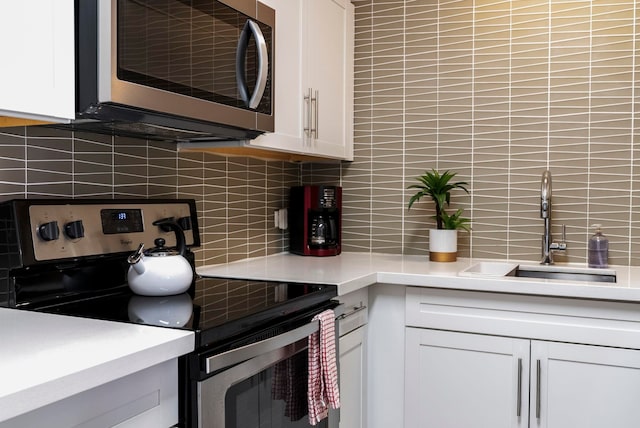 kitchen featuring tasteful backsplash, sink, white cabinets, and stainless steel appliances