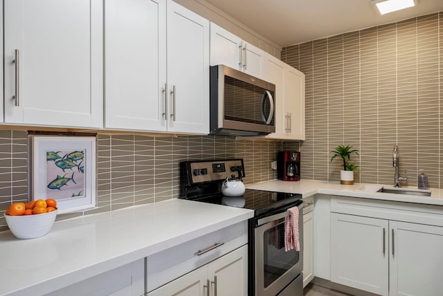 kitchen featuring white cabinets, appliances with stainless steel finishes, backsplash, and sink