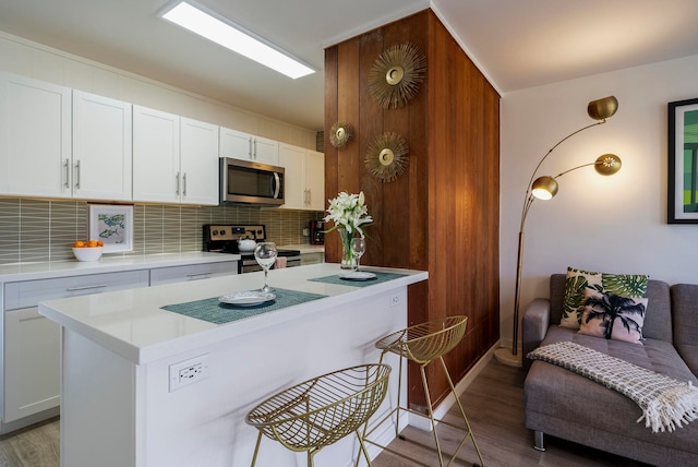 kitchen featuring white cabinets, decorative backsplash, stainless steel appliances, and light hardwood / wood-style flooring