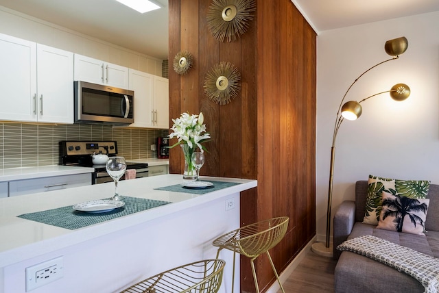 kitchen featuring wood-type flooring, white cabinetry, stainless steel appliances, and tasteful backsplash