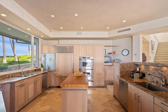 kitchen featuring butcher block counters, light brown cabinets, stainless steel appliances, and sink