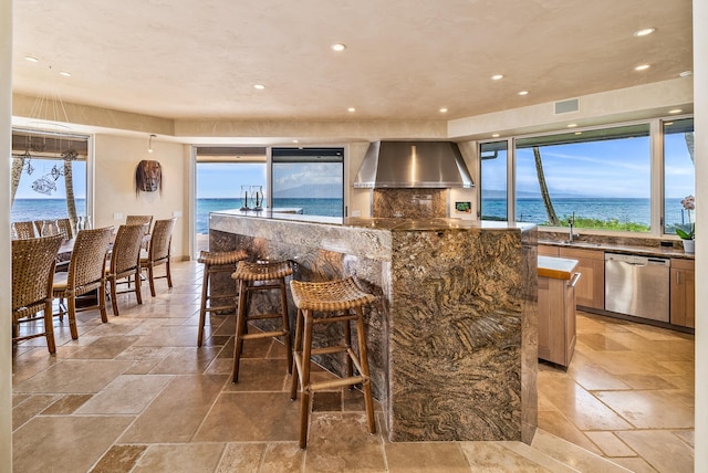 kitchen with dishwasher, a water view, wall chimney range hood, and plenty of natural light