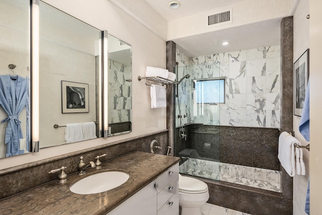 bathroom featuring vanity, toilet, and a tile shower