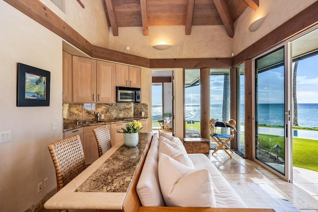 kitchen with light brown cabinets, wooden ceiling, a water view, tasteful backsplash, and beam ceiling