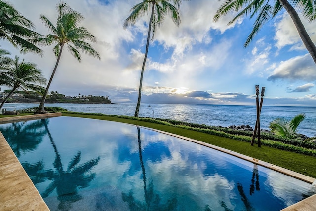 view of swimming pool featuring a lawn and a water view