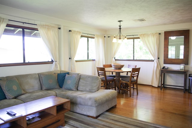 living room with an inviting chandelier, a healthy amount of sunlight, and hardwood / wood-style floors