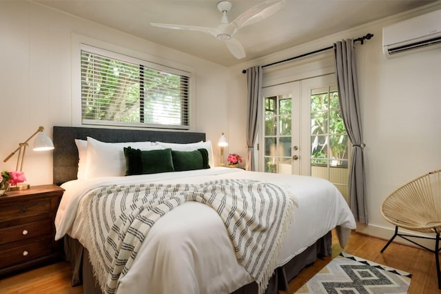 bedroom with an AC wall unit, hardwood / wood-style floors, french doors, access to exterior, and ceiling fan