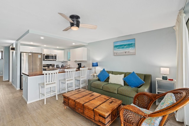 living room with ceiling fan and light hardwood / wood-style floors