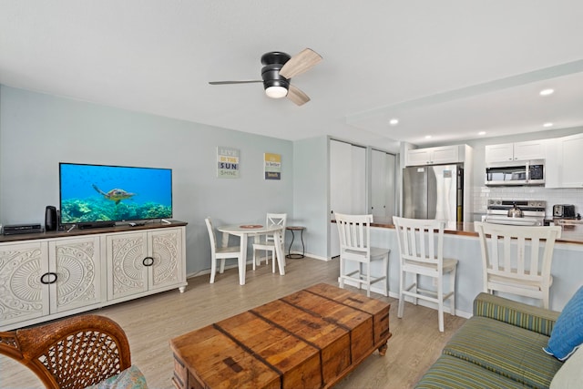 living room with light hardwood / wood-style flooring and ceiling fan