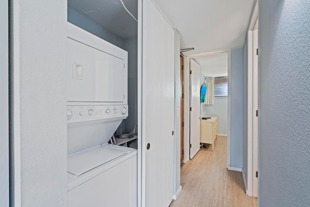 laundry area with light hardwood / wood-style flooring and stacked washer / dryer