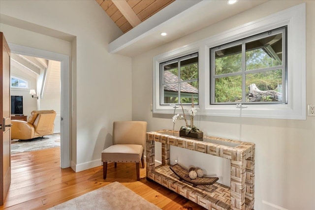 living area featuring lofted ceiling with beams and light hardwood / wood-style flooring