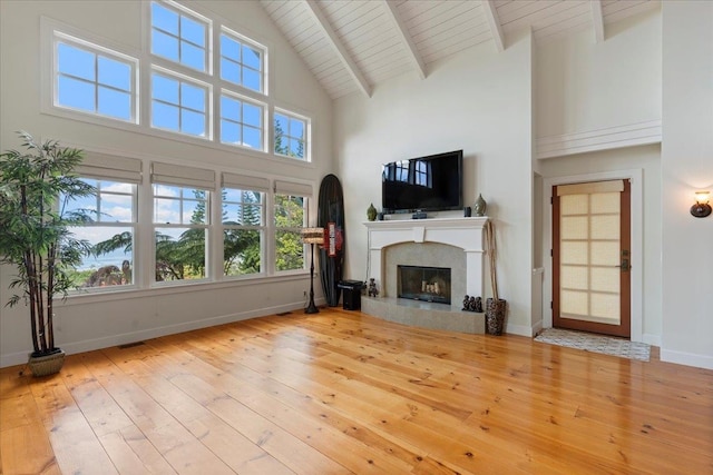 unfurnished living room with high vaulted ceiling, light hardwood / wood-style flooring, beam ceiling, and wooden ceiling