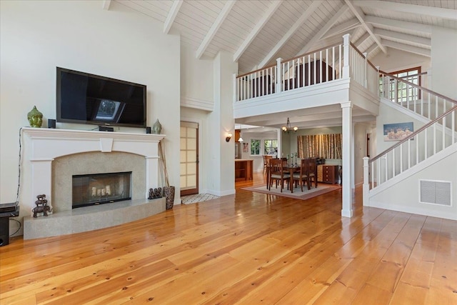 living room featuring wooden ceiling, beamed ceiling, high vaulted ceiling, hardwood / wood-style floors, and a fireplace