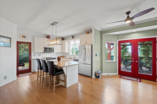 kitchen with white cabinets, appliances with stainless steel finishes, and ornamental molding