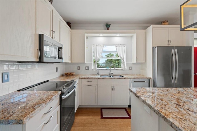 kitchen with tasteful backsplash, light stone counters, a sink, light wood finished floors, and stainless steel appliances