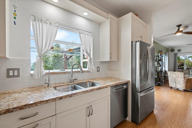 kitchen featuring crown molding, appliances with stainless steel finishes, decorative backsplash, and a sink