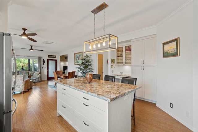 kitchen with visible vents, freestanding refrigerator, a breakfast bar, open floor plan, and a ceiling fan