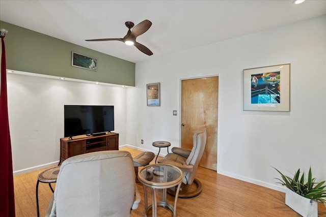 living area with baseboards, ceiling fan, and wood finished floors