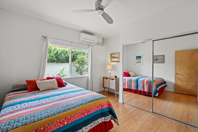 bedroom featuring baseboards, a wall mounted air conditioner, a closet, and wood finished floors