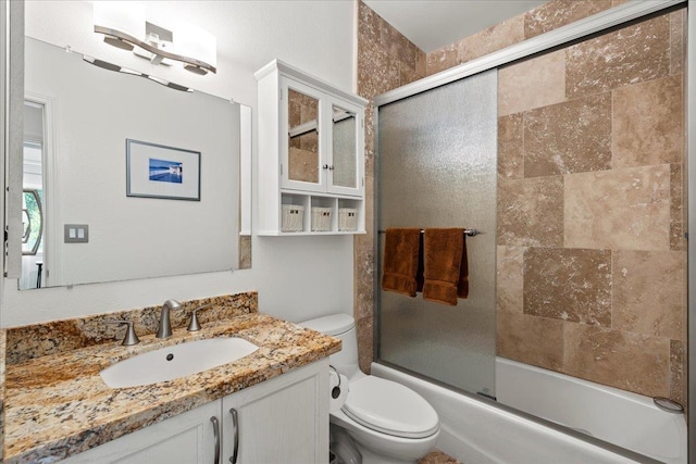 bathroom featuring toilet, shower / bath combination with glass door, and vanity