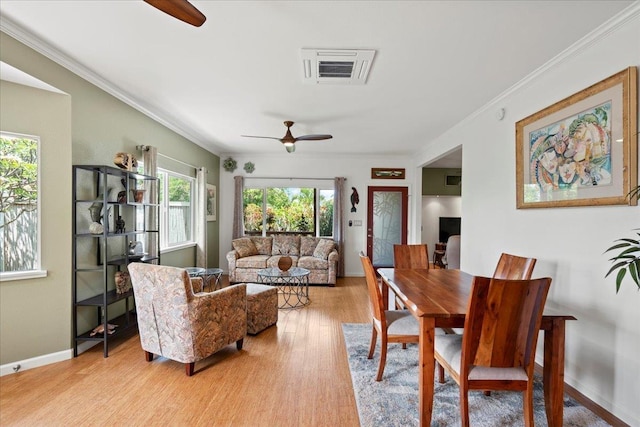 dining area featuring light wood-type flooring, a ceiling fan, crown molding, and visible vents