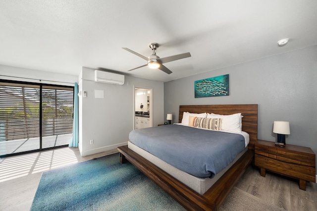 bedroom featuring connected bathroom, an AC wall unit, ceiling fan, hardwood / wood-style flooring, and access to outside