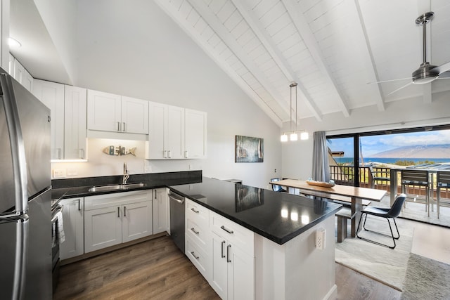 kitchen with kitchen peninsula, white cabinets, appliances with stainless steel finishes, beamed ceiling, and sink