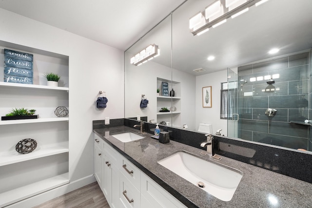 bathroom with toilet, hardwood / wood-style flooring, an enclosed shower, built in features, and vanity