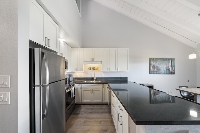 kitchen with dark wood-type flooring, white cabinetry, appliances with stainless steel finishes, beamed ceiling, and sink